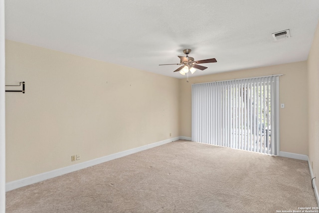 carpeted spare room with visible vents, a ceiling fan, and baseboards