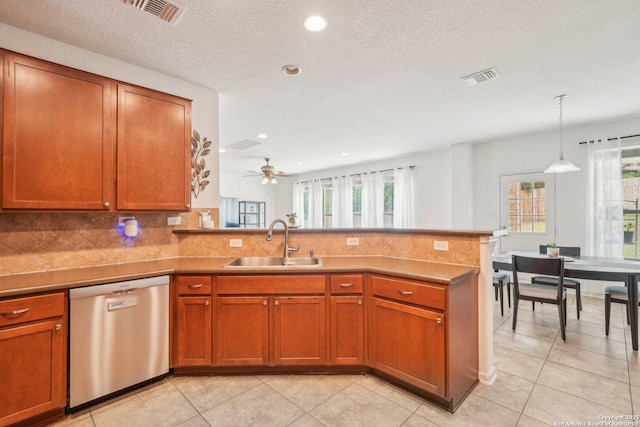 kitchen with a sink, light tile patterned floors, dishwasher, a peninsula, and visible vents