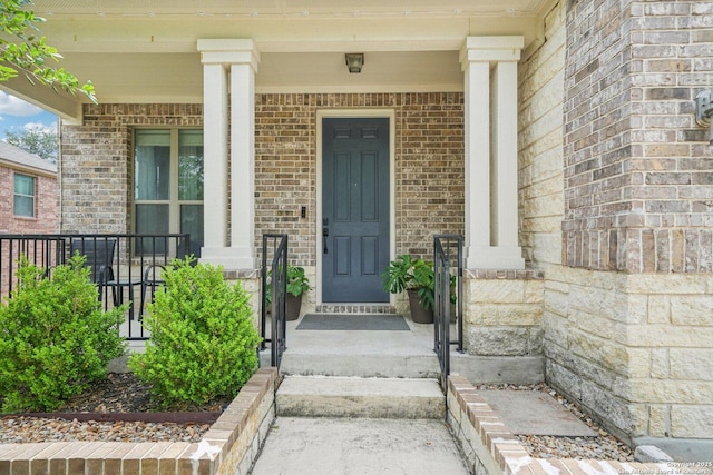 view of exterior entry with brick siding and covered porch