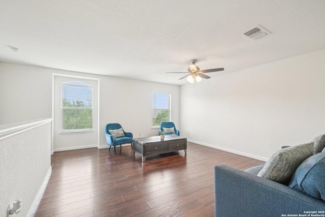 living area featuring visible vents, a ceiling fan, baseboards, and dark wood-style flooring