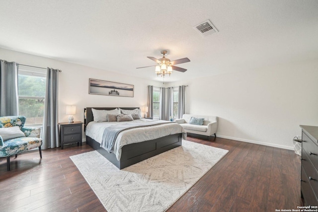 bedroom featuring dark wood-style flooring, baseboards, visible vents, and multiple windows