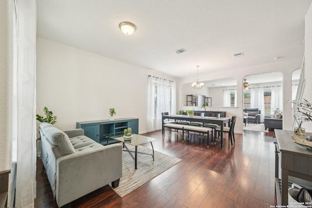 living room with visible vents, a chandelier, and dark wood finished floors