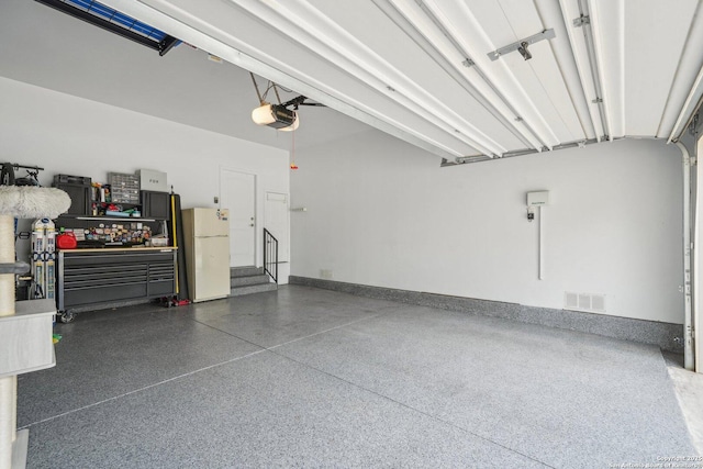garage featuring freestanding refrigerator, visible vents, and a garage door opener