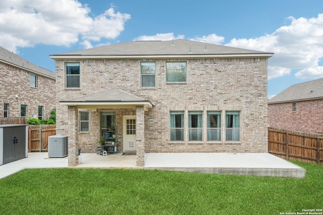 rear view of house with a fenced backyard, central AC, brick siding, a patio area, and a yard