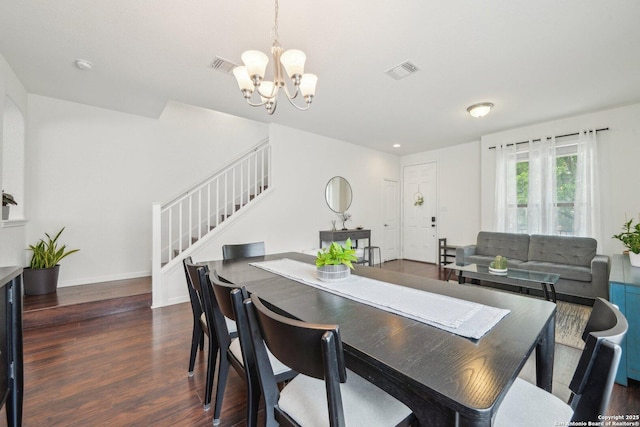 dining area with dark wood-type flooring, a notable chandelier, stairs, and visible vents