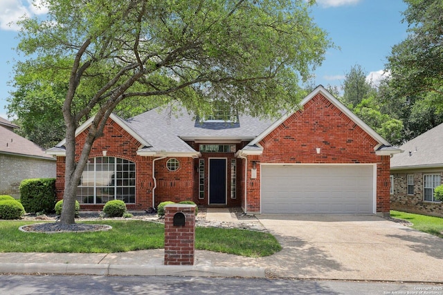 traditional-style house with a shingled roof, concrete driveway, brick siding, a front yard, and a garage