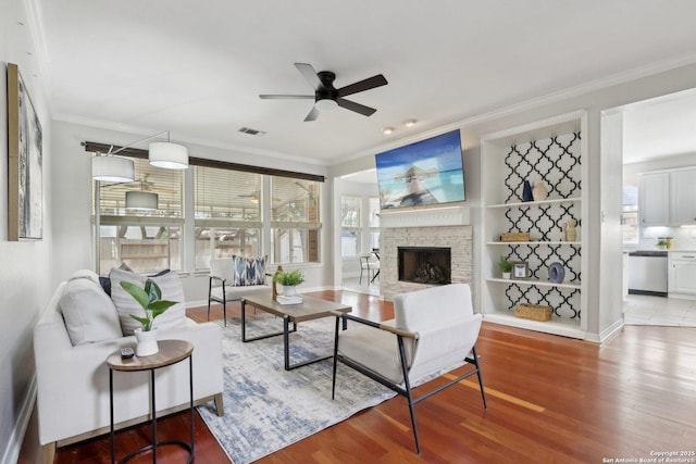 living room featuring ceiling fan, visible vents, wood finished floors, and ornamental molding