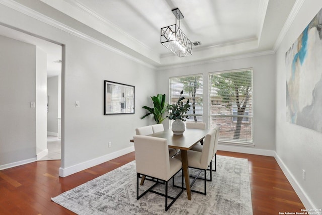 dining room with a raised ceiling, wood finished floors, and ornamental molding