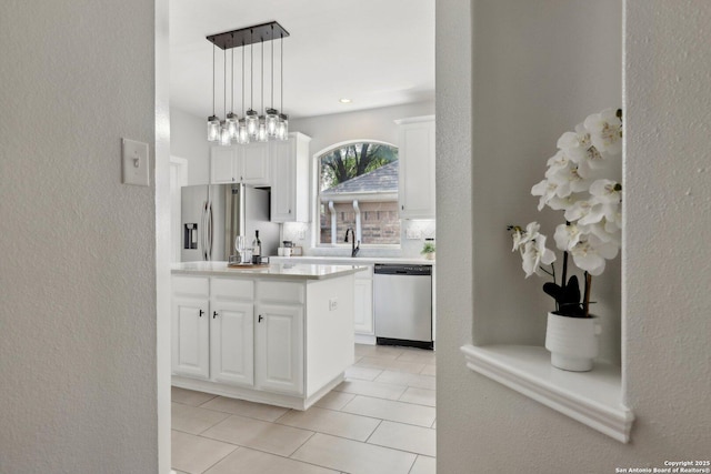 kitchen featuring white cabinets, stainless steel appliances, light countertops, a sink, and light tile patterned flooring