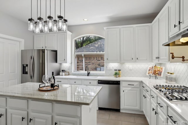 kitchen featuring tasteful backsplash, a sink, appliances with stainless steel finishes, white cabinetry, and under cabinet range hood