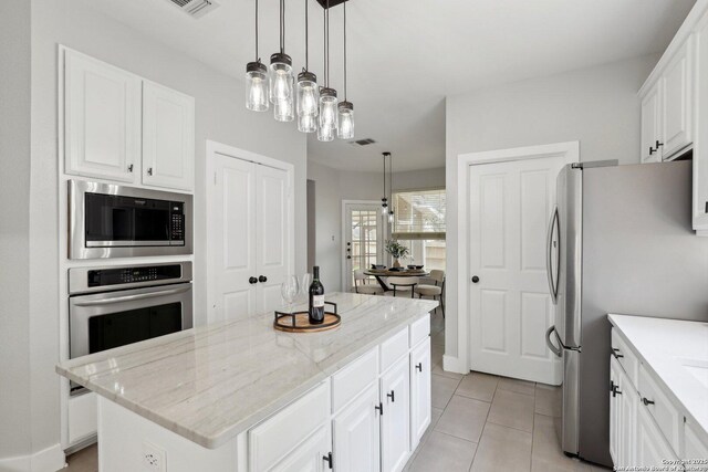 kitchen with white cabinets, a center island, visible vents, light stone countertops, and appliances with stainless steel finishes