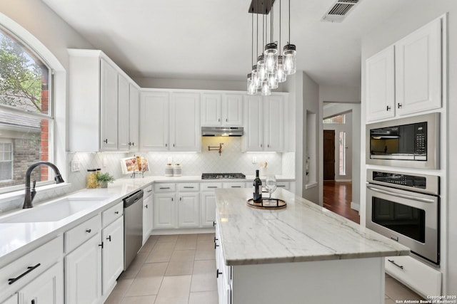 kitchen featuring white cabinets, under cabinet range hood, stainless steel appliances, visible vents, and a sink