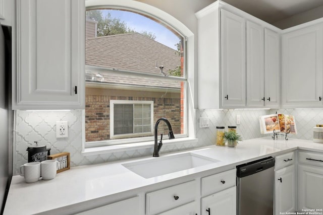kitchen with dishwasher, decorative backsplash, white cabinetry, and a sink
