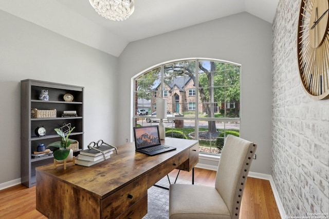 home office featuring vaulted ceiling, a notable chandelier, light wood-style flooring, and plenty of natural light