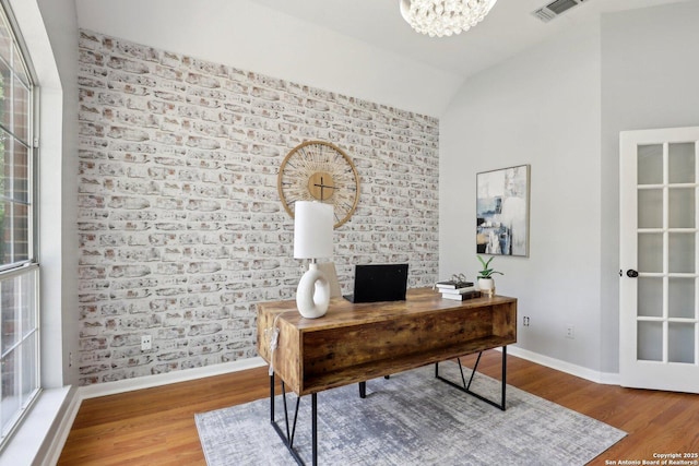 office space featuring vaulted ceiling, wood finished floors, visible vents, and baseboards