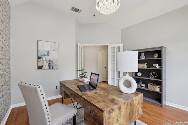 office featuring lofted ceiling, wood finished floors, baseboards, and a notable chandelier