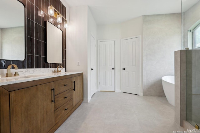 bathroom featuring tile patterned flooring, a freestanding tub, a sink, and double vanity