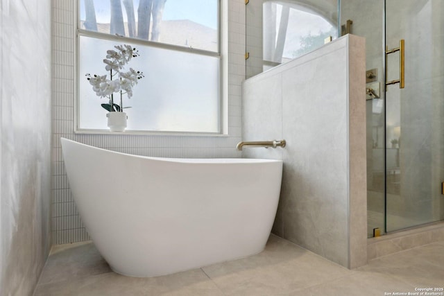full bathroom with a freestanding tub, a shower stall, a healthy amount of sunlight, and tile patterned flooring