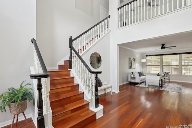 stairs with wood finished floors, a ceiling fan, and baseboards
