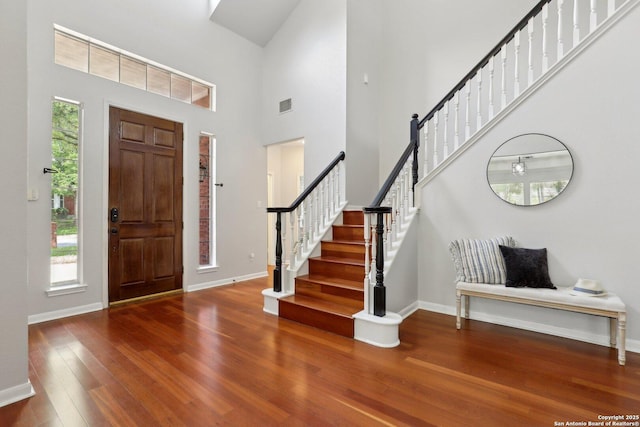 foyer with a high ceiling, wood finished floors, visible vents, baseboards, and stairs