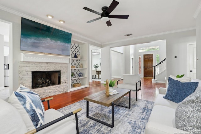 living room with visible vents, wood finished floors, stairs, ceiling fan, and ornamental molding