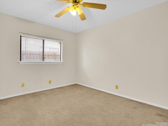 carpeted spare room featuring a ceiling fan and baseboards