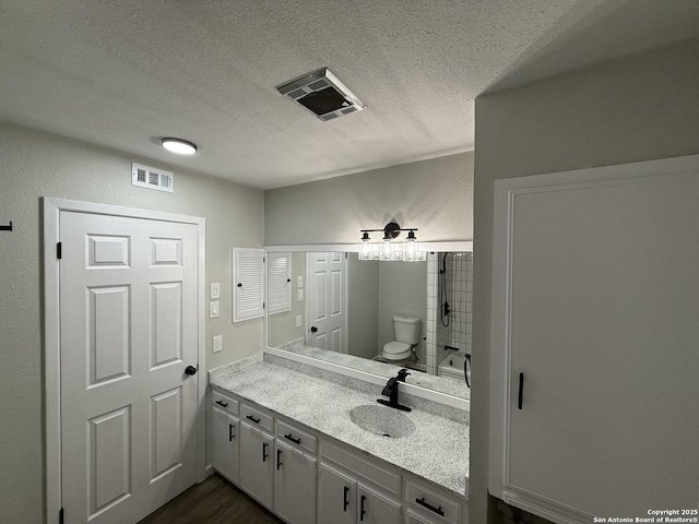 bathroom with a textured ceiling, visible vents, toilet, and vanity