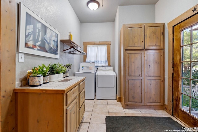 laundry room featuring washer and dryer, cabinet space, and light tile patterned flooring