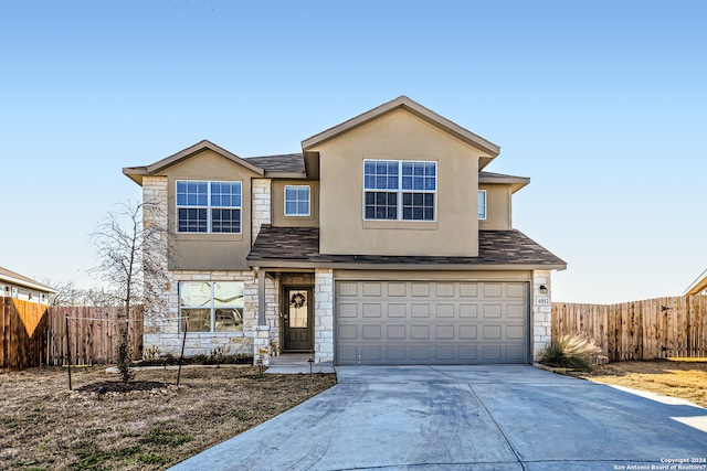 traditional home featuring stucco siding, fence, stone siding, and concrete driveway
