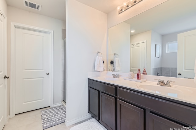 full bath featuring a shower with shower door, double vanity, visible vents, and a sink