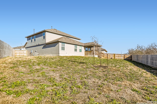 rear view of house with a fenced backyard and a lawn