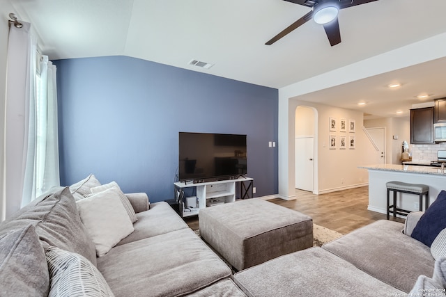 living area with light wood-style flooring, vaulted ceiling, baseboards, visible vents, and ceiling fan