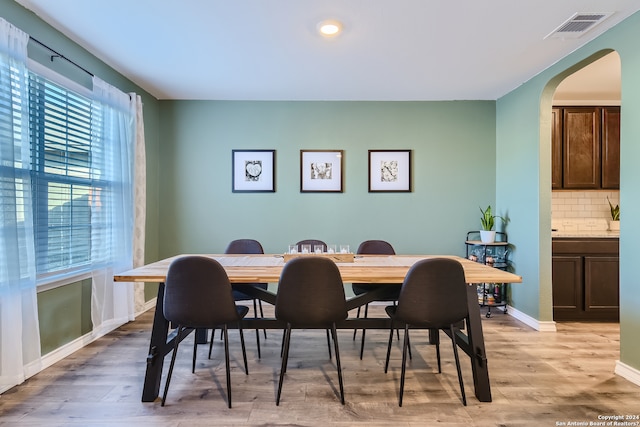 dining room with arched walkways, light wood finished floors, baseboards, visible vents, and recessed lighting