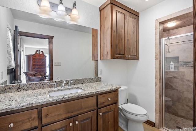 bathroom featuring a stall shower, vanity, and toilet