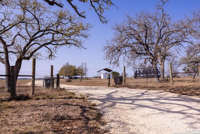 view of street with a gated entry and gravel driveway