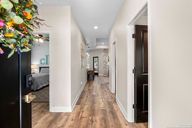 corridor featuring baseboards, wood finished floors, and recessed lighting