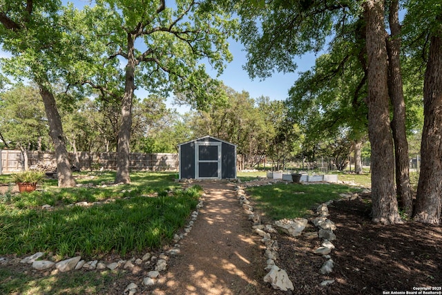 view of yard with fence, an outdoor structure, and a storage shed