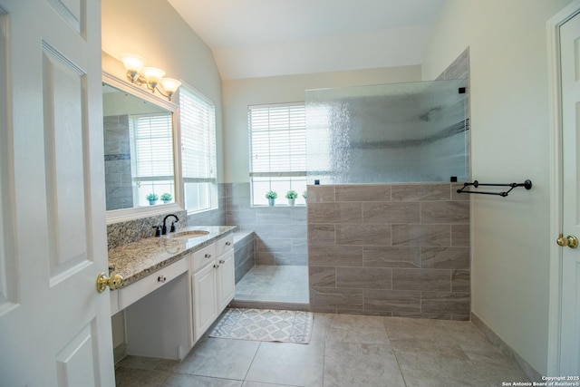 511 Mesa Rdg, San Antonio, TX 78258 - bathroom with lofted ceiling, tile patterned floors, vanity, tile walls, and walk in shower