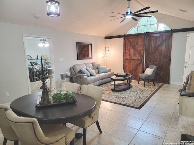 living area featuring a barn door, vaulted ceiling, visible vents, light tile patterned floors, and ceiling fan