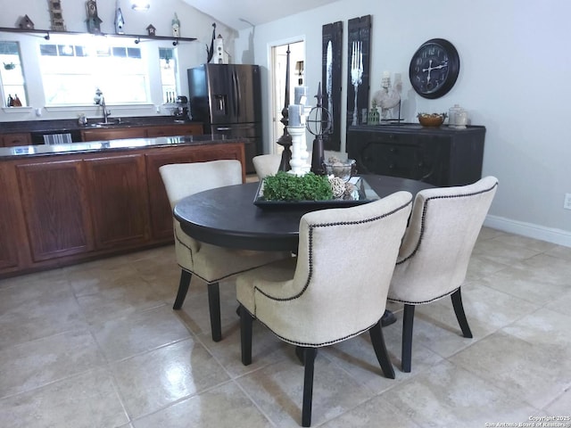 dining space with light tile patterned floors, vaulted ceiling, and baseboards