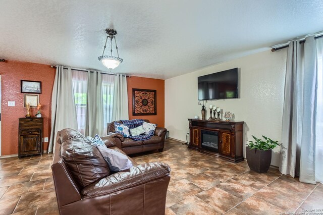 5402 Palamon Farm, San Antonio, TX 78228 - living room with stone finish floor, a textured wall, baseboards, a glass covered fireplace, and a textured ceiling