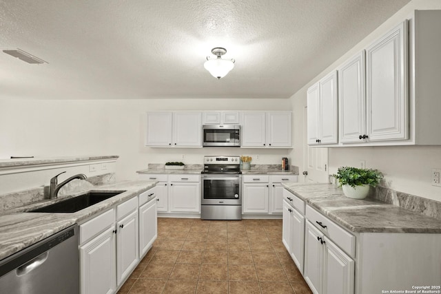 kitchen featuring a textured ceiling, a sink, visible vents, white cabinetry, and appliances with stainless steel finishes
