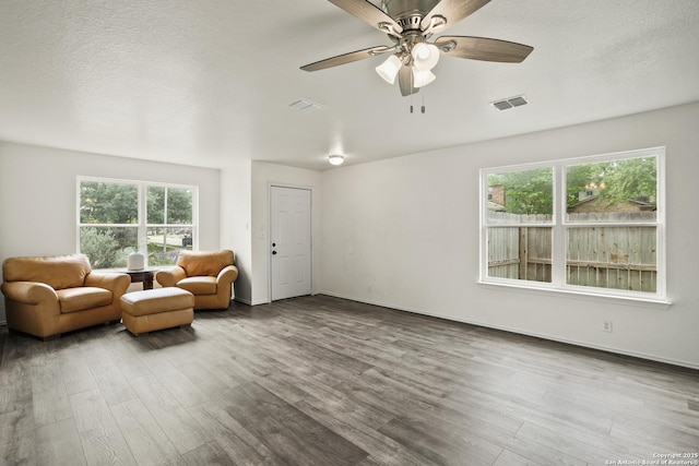 sitting room with wood finished floors, visible vents, and a ceiling fan