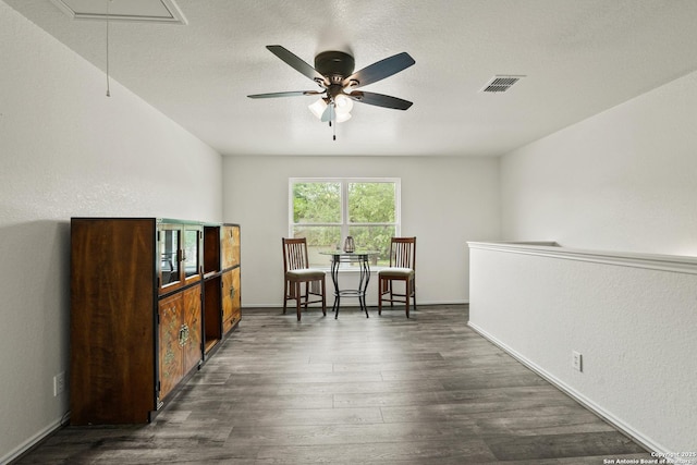 interior space with a ceiling fan, attic access, baseboards, dark wood-style flooring, and visible vents