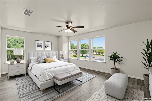 bedroom with baseboards, wood finished floors, visible vents, and a ceiling fan