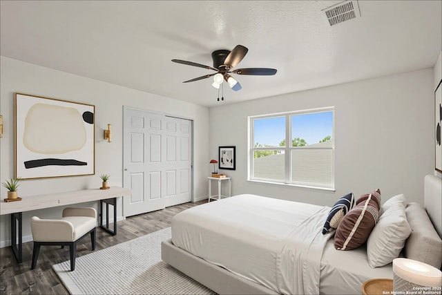 bedroom featuring wood finished floors, visible vents, a ceiling fan, and baseboards
