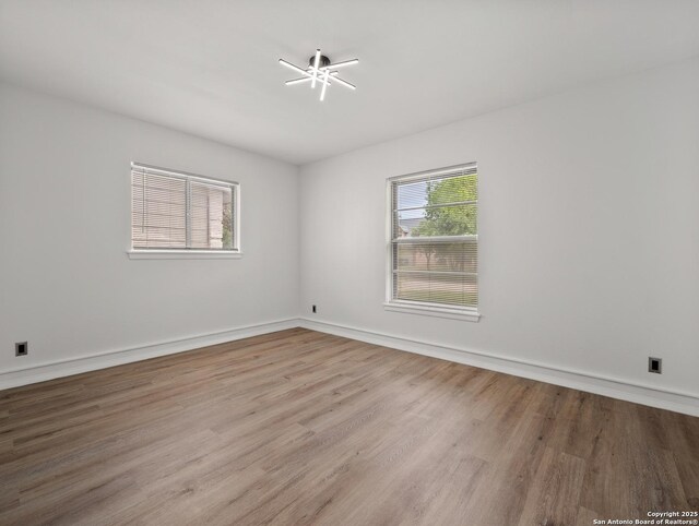 spare room featuring baseboards and wood finished floors