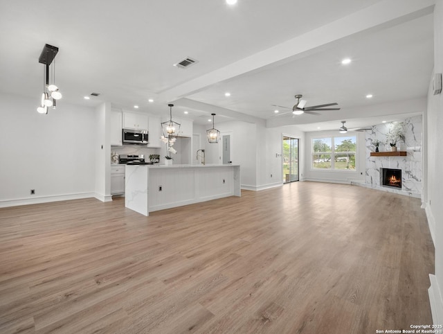 unfurnished living room featuring recessed lighting, a stone fireplace, light wood-type flooring, baseboards, and ceiling fan