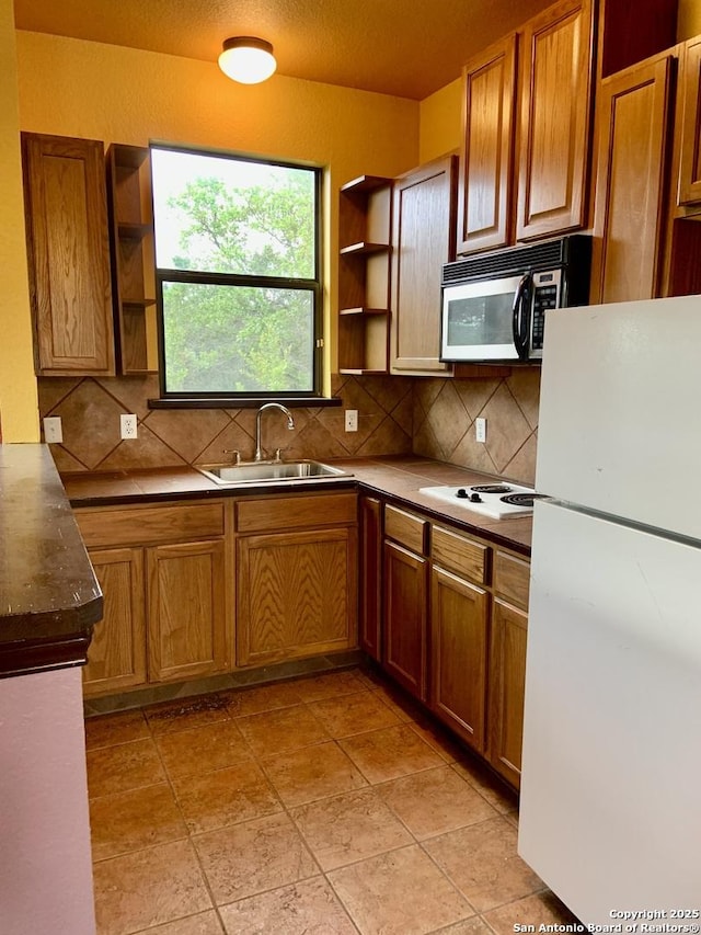 kitchen featuring open shelves, a sink, brown cabinetry, white appliances, and backsplash