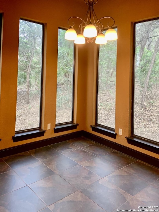 unfurnished dining area with a chandelier, a healthy amount of sunlight, and baseboards
